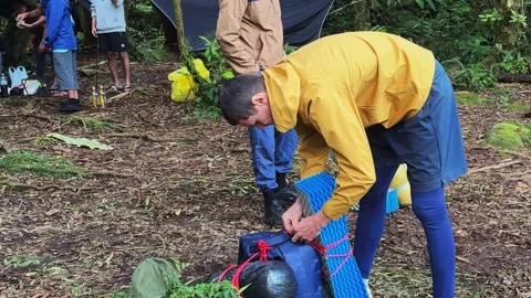 Man attaches sleeping pad to backpack at wilderness journey Stock-Footage 346946875