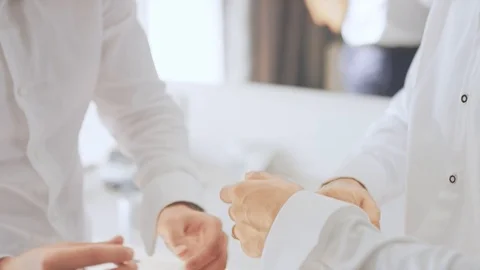 A man is attaching the arm's button of the groom.  Stock Footage 90975493