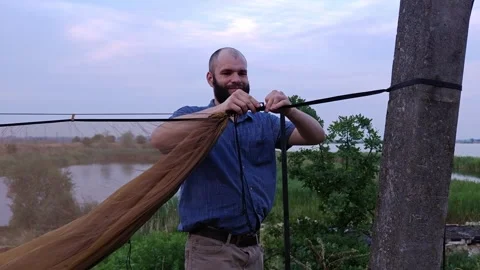 Man attaching camping hammock to strap on pole outdoors Stock-Footage 339591900
