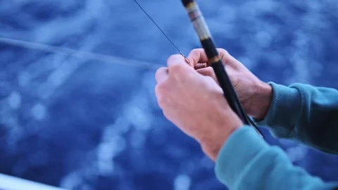Man Attaching Fishing Lure While Yacht Sails Across Deep Blue Ocean Waters Stock Footage 303255483