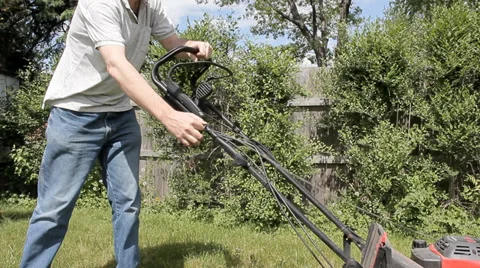 Man attempting to start broken lawn mower Stock Footage 38926289