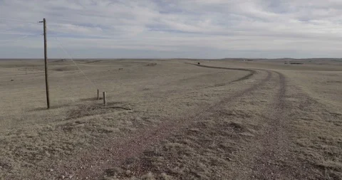 Man On ATV Driving Past Camera On Winding Gravel Road In Dry Field Stock-Footage 100483314