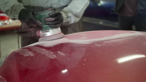 Man auto mechanic uses a grinder to grind a putty on a damaged car body part Stock Footage 153488134