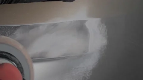 A man auto mechanic uses a grinder to grind a putty on a damaged car body part.  Video stock 202168539