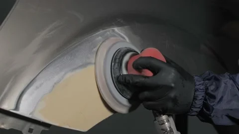 A man auto mechanic uses a grinder to grind a putty on a damaged car body part.  Video stock 202169685