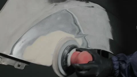 A man auto mechanic uses a grinder to grind a putty on a damaged car body part. Video stock 202170621
