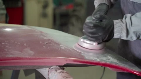 Man auto mechanic using a grinder removes paint from a damaged car body part Stock Footage 153489006