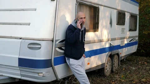 A man in the autumn forest is talking on the phone standing near a mobile van. Stock Footage 295194656