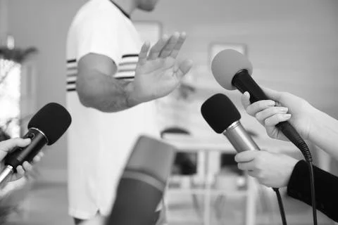 Man avoiding journalist's questions at interview indoors, closeup. Black an.. Stock Photos