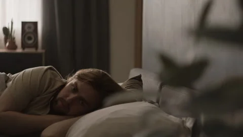 Man Awakening in Bed Staring at Ceiling during Morning at Home 動画素材 345513094