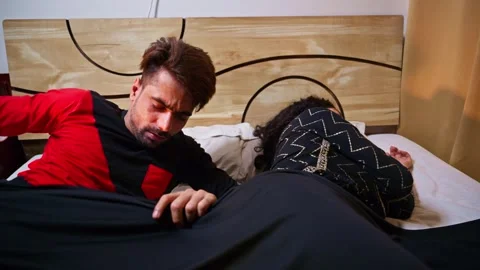 Man awakening with a stretch while lady still sleeping Stock Footage 300360881