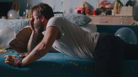 Man awaking in trashed room after party Foto stock