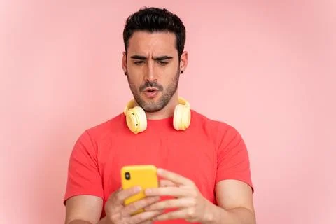 Man in awe while looking at social networks on mobile phone. Stock Photos