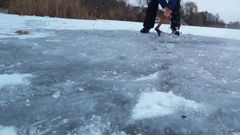Man with an ax chopping ice for an ice-hole Stock Footage 85559345