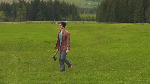 Man with ax is walking on the mountain countryside Stock Footage 76247443