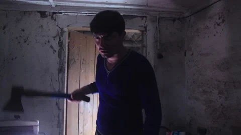 A man with an axe standing in a dark room, deep breathing,looking at the camera Stock-Footage 137133742