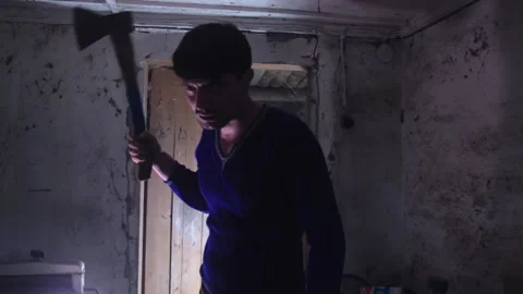 A man with an axe standing in a dark room, deep breathing,looking at the camera Stock-Footage 138539656