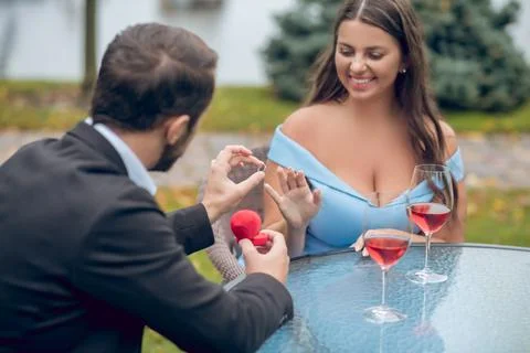 Man with back to camera putting ring on woman Stock Photos