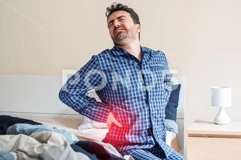 Man with back pain in bed feeling pain Stock Photos