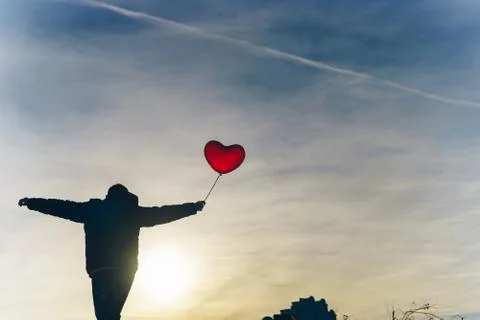 Man from the back with a red balloon in hand against the blue sky on frosty day 스톡 사진