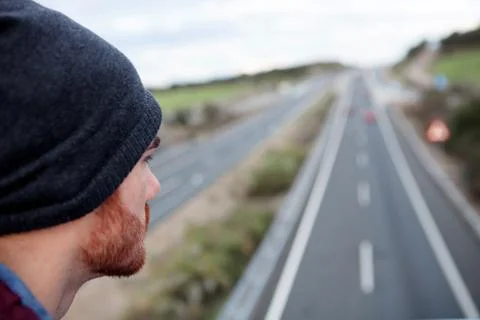 Man back at the top of a bridge over a highway Stock Photos