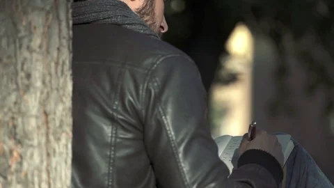 Man back while  writing on a notebook under a tree Stock Footage 71891594