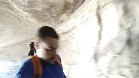 Man with backack hiking through a cave holding an action cam Stock Footage 113301491