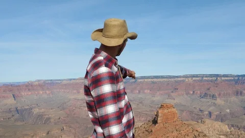 Man On The Background Of The Grand Canyon Points His Hand At The Rock Monument Stock Footage 90963655