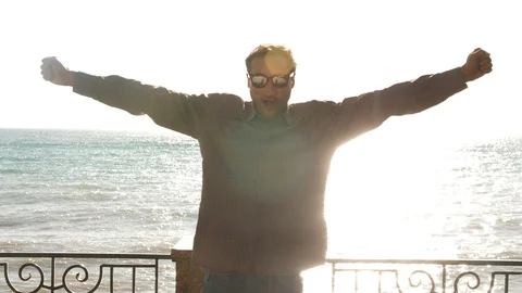 Man on the background of the sea in the sun dancing for joy Stock Footage 97064214