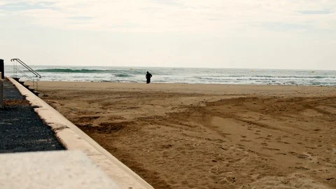 A man in the background standing on the shore of a beach Stock Footage 101347125