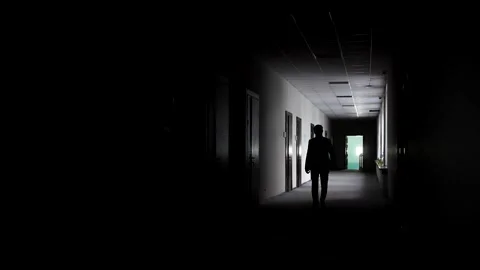 A man in the backlit walks down a long hallway Stock Footage 152008247