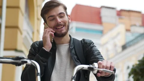 Man with backpack and bicycle stands on street and communicates via smartphone Video stock 143425272
