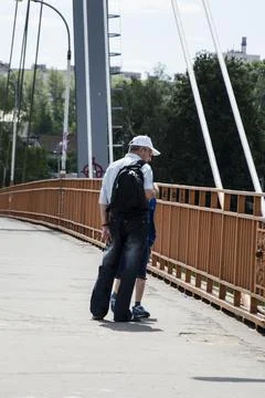 A man with a backpack and a cap walks along the pedestrian bridge. Stock Photos