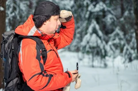 A man with a backpack and a compass got lost in a snowy forest Stock Photos