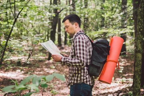 Man with Backpack and map searching directions in wilderness area. Tourist with Foto stock