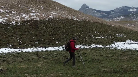 A man with a backpack and Nordic walking sticks goes on a hike to a mountain ran Stock Footage 150564877