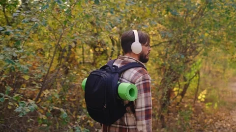 A man with a backpack and sleeping mat walks away from the camera, enjoying the Stock Footage 278277367