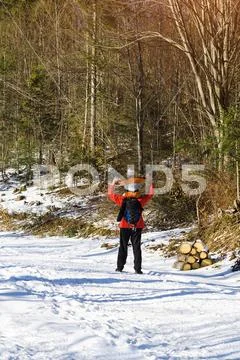 Man with backpack and son on shoulders stands with arms raised against the ba Stock Photos