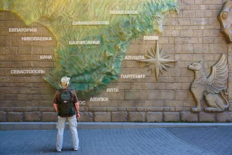 A man with a backpack on a background map of the Crimea. Alushta. Stock Photos