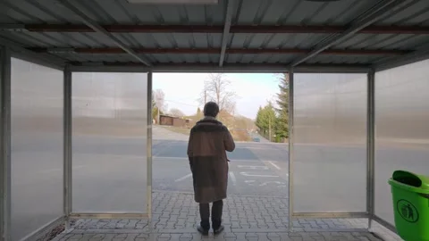 Man with backpack at bus stop, waiting and looking around. Everyday urban Stock Footage 333286824