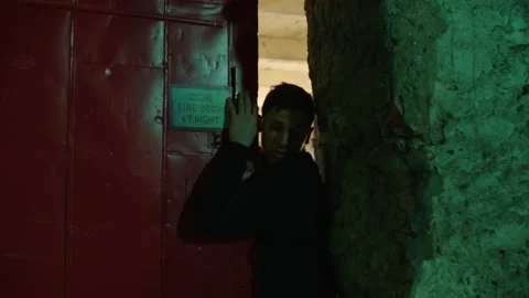 Man with backpack on is chased in a warehouse and through an industrial door, in Stock Footage 199461879