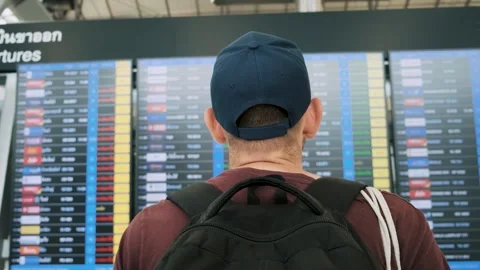 Man with backpack checking flight information on digital board at an airport Stock Footage 277984035