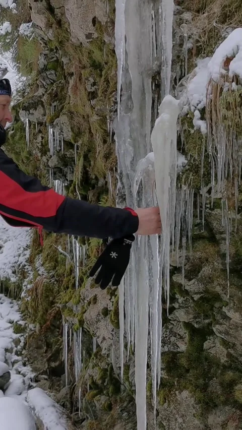 Man with a backpack comes up and bounces off a large icicle. Stock Footage 220412760