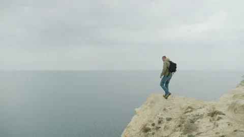 A man with a backpack comes to the edge of a cliff with a beautiful view of the Video stock 172444289