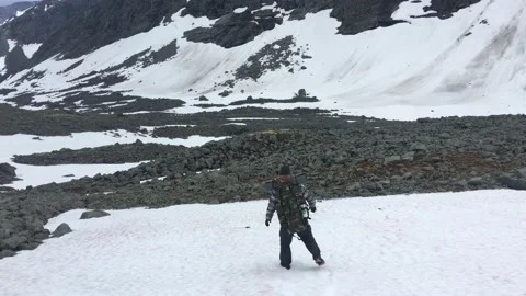 A man with a backpack descends a snow-covered slope in the mountain Stock Footage 207686908