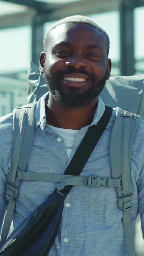 A man with a backpack explores a vibrant city, smiling at the camera Stock Footage 305950873
