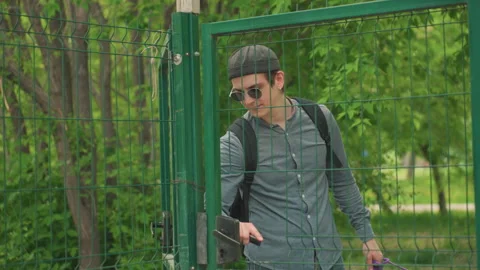 Man with backpack exploring nature, casual summer stroll through city greenery Vidéo 323328843