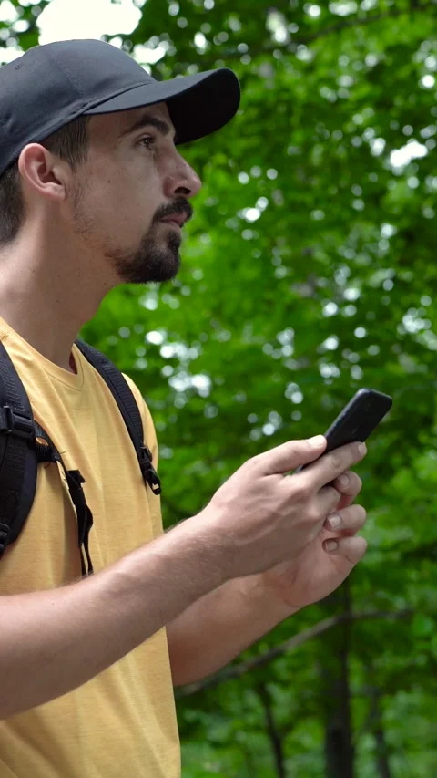 Man with backpack in forest uses phone looking for connection signal 스톡 동영상 279307838