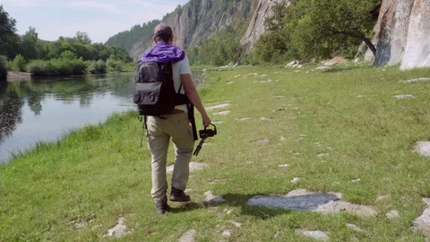 A man with a backpack goes along the river. Stock Footage 115259823