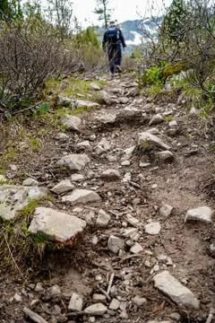 A man with backpack is going on the stony mountain path Stock Photos